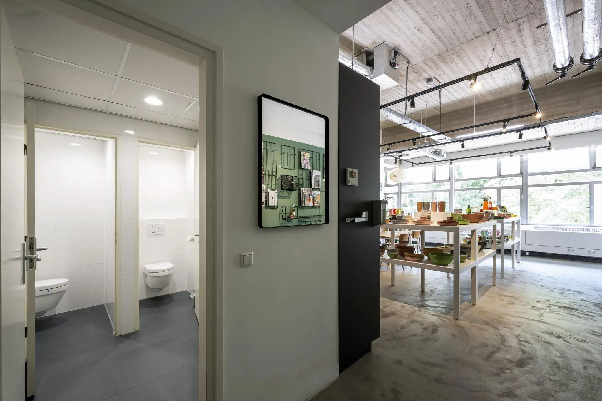 Moderne kantoorruimte aan de Van Leijenberghlaan met zicht op toiletgedeelte en ingerichte presentatieruimte met servies en keukengerei.